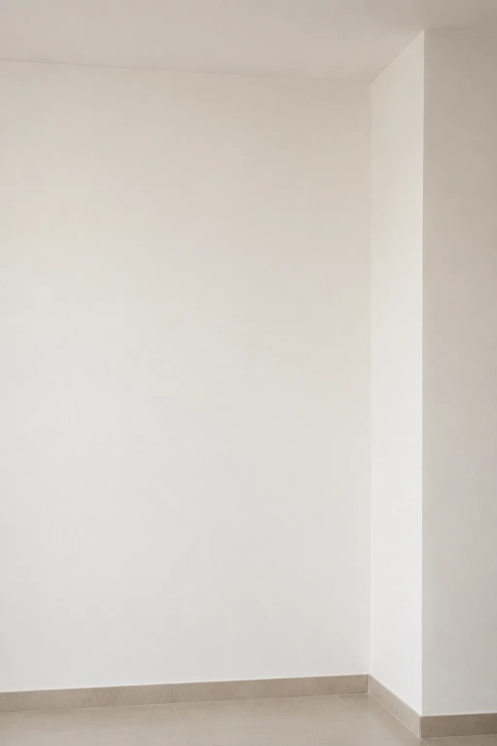 Angle de pièce avant intervention : deux murs blancs nus, sol carrelé beige.
